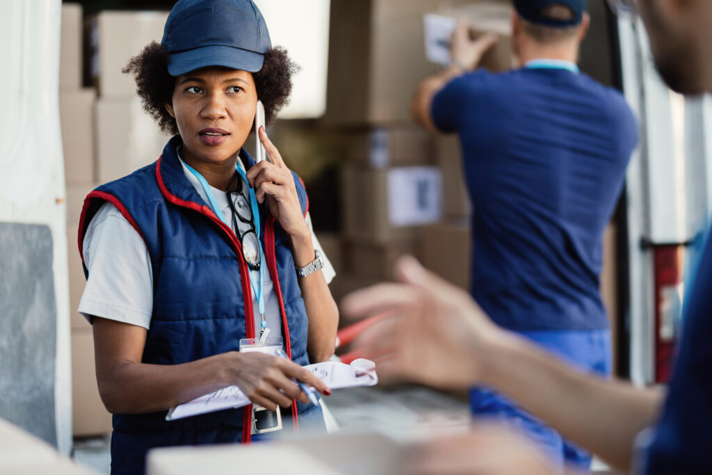 African American worker using phone while talking to her colleag. Custom clearance agent in Dubai